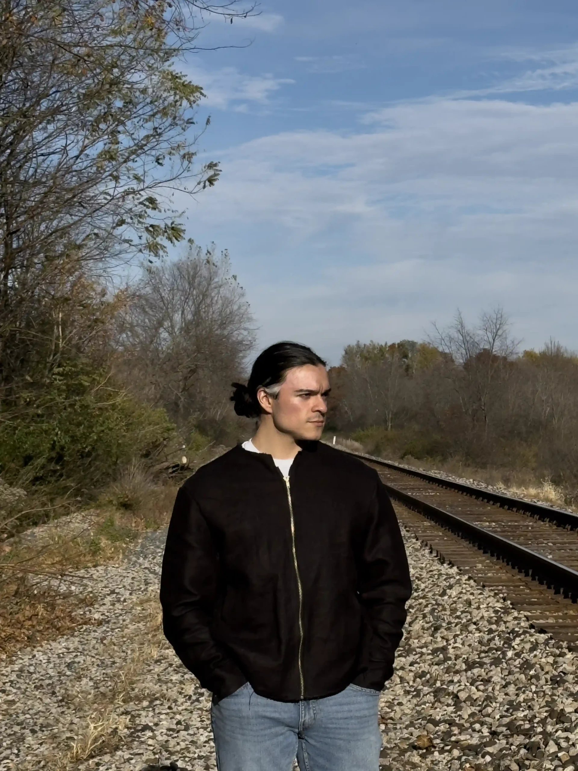 Anthony Mikinka wearing black StructuredDenim Hemp Coat, looking off to the side, showcasing rugged hemp linen canvas and stylish winter design.